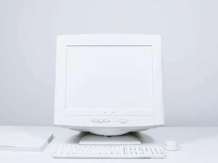 White desktop monitor, keyboard, and mouse on a table