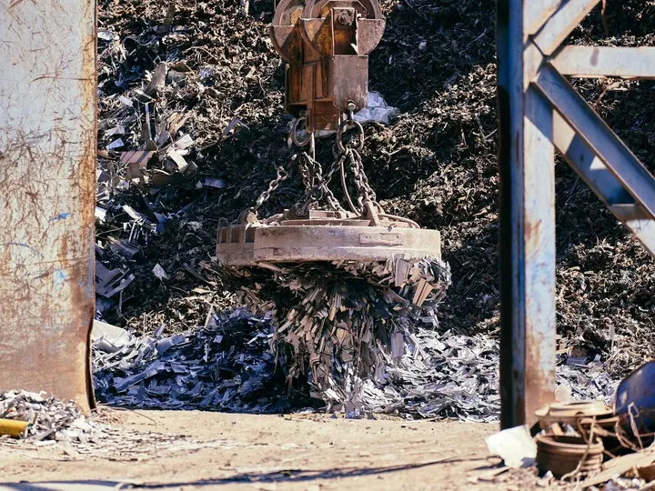 Magnet crane lifting metal scrap in a recycling yard